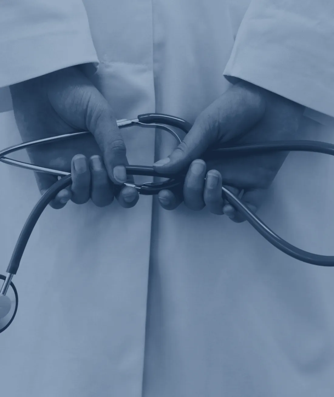 Doctor in a white coat holding a stethoscope behind their back